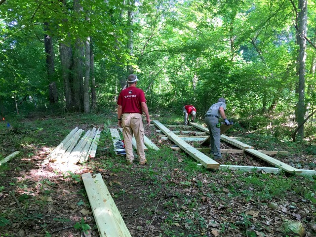 photo of three men working on laying out a wooden bridge framework for a pedestrian footbridge on the HRT