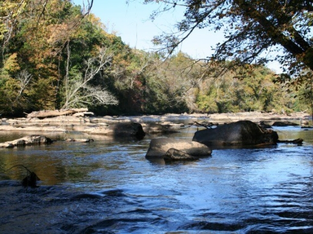 a photo of the Haw River in the Fall in the Glencoe section with rocks in the river
