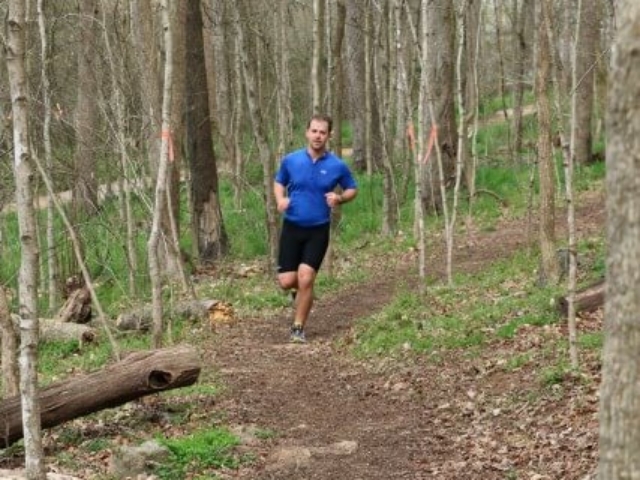 photo of a man in a blue shirt and black shorts running on the HRT in Saxapahaw