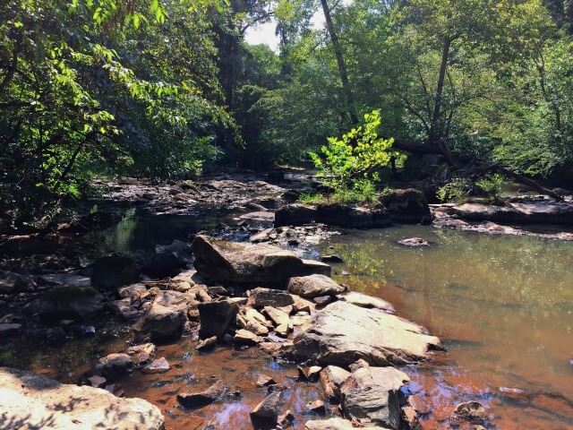 a photo of rocks and trees and the Haw River at Brooks Bridge Paddle Access