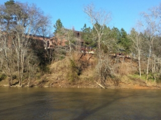 photo looking across the calm Haw River from Saxapahaw Island up to the Rivermill buildings
